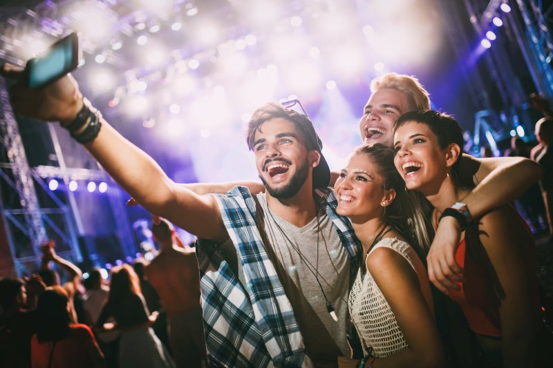 Happy young friends taking selfie at music festival